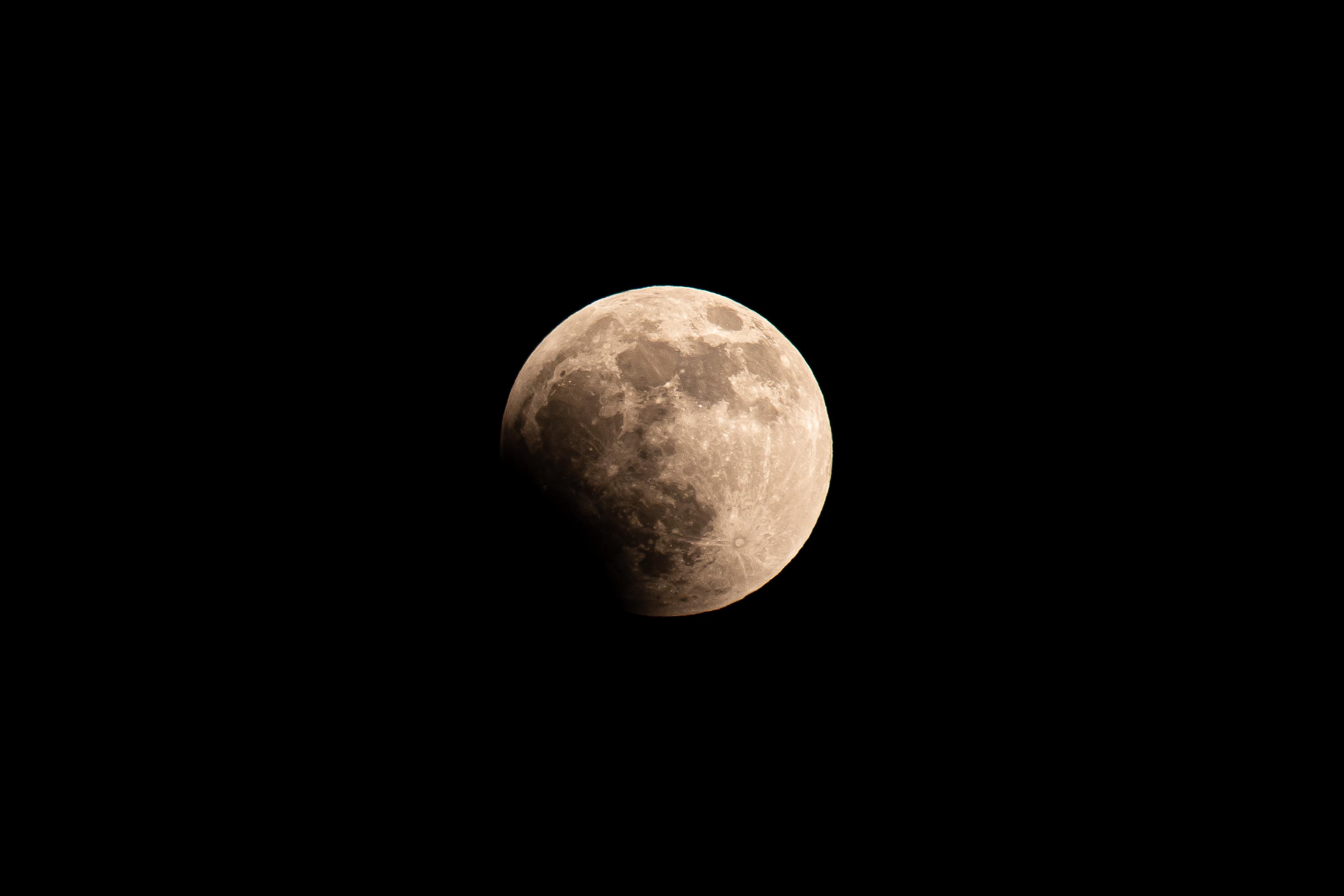 The full moon during the early stages of a lunar eclipse, showing the lower left portion covered in shadow