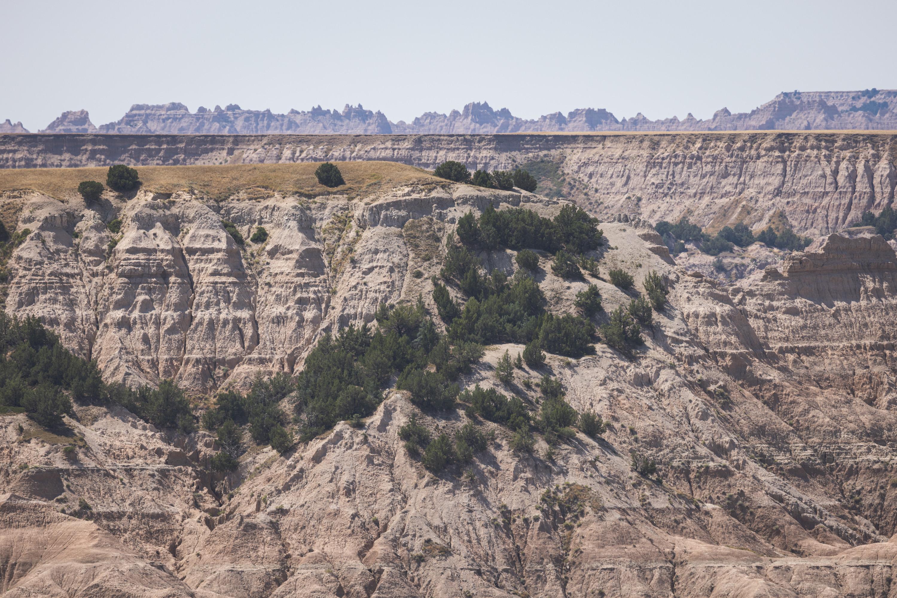 A view of rounded cliffs which lead down into a deep valley, whose sides are covered in light brush