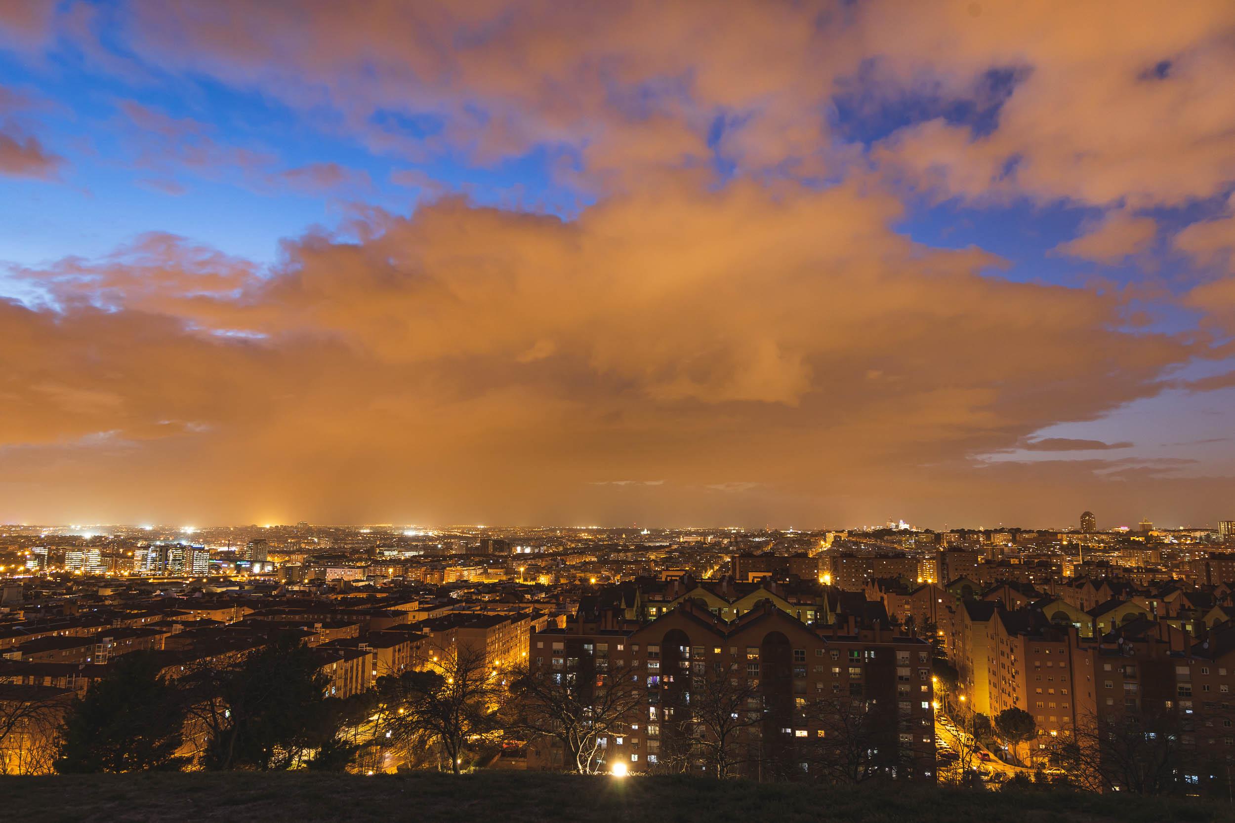Fluffy clouds follow rainshowers as the sun sets in the sky over Madrid