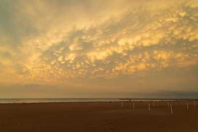 Clouds in a round fluffy formation in the orange-tinted sky as a storm front passes through.