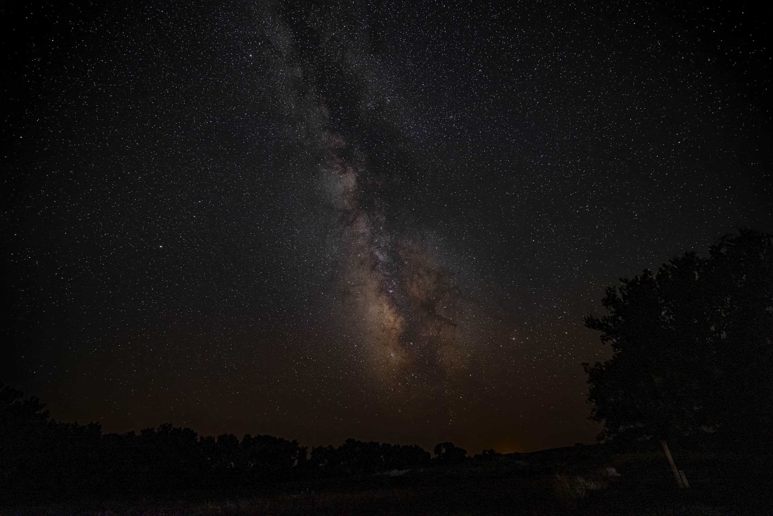 A photo of the Milky Way and thousands of stars above the horizon.