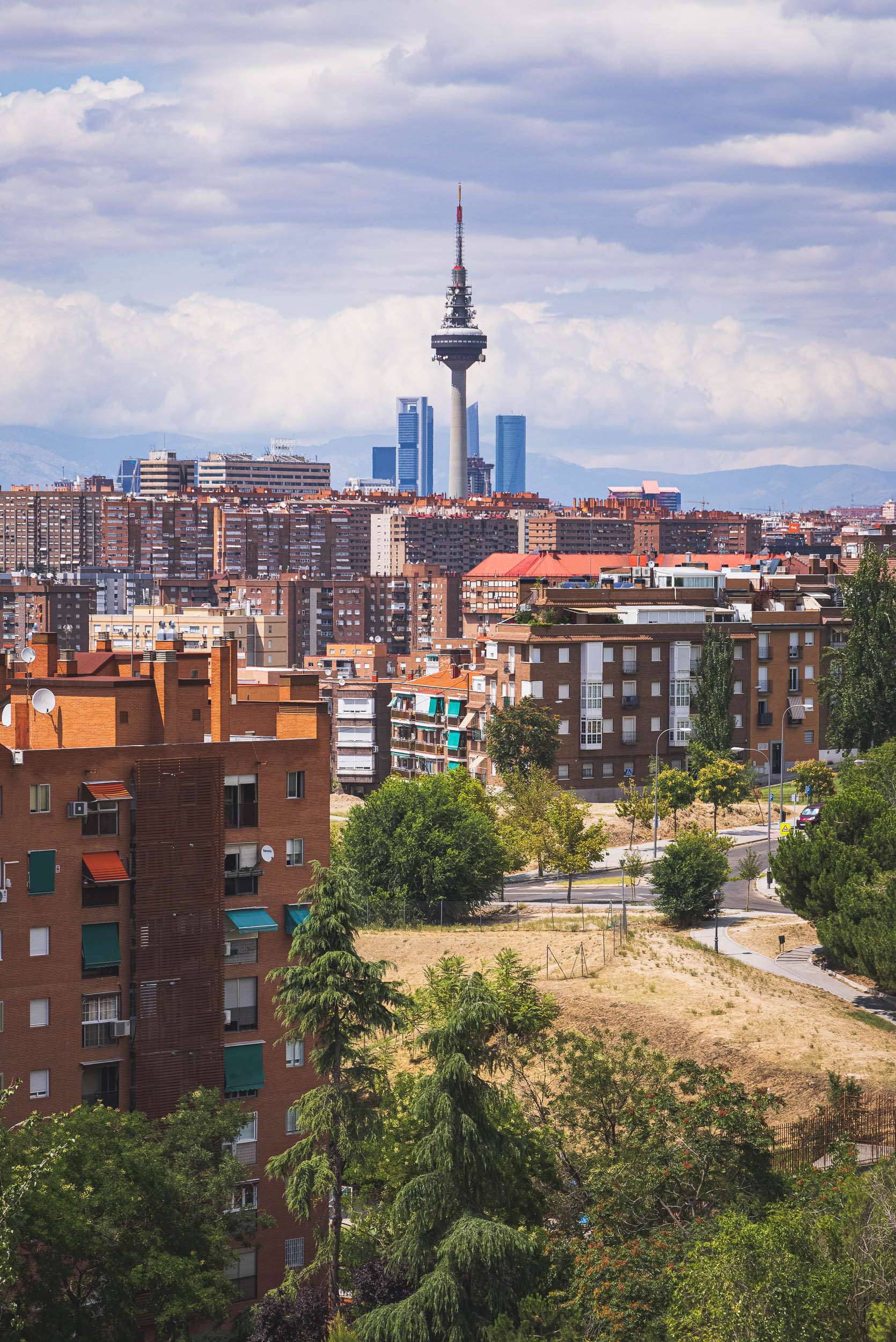 A photo of the Madrid skyline featuring apartment buildings in the foreground and tall towers on the horizon