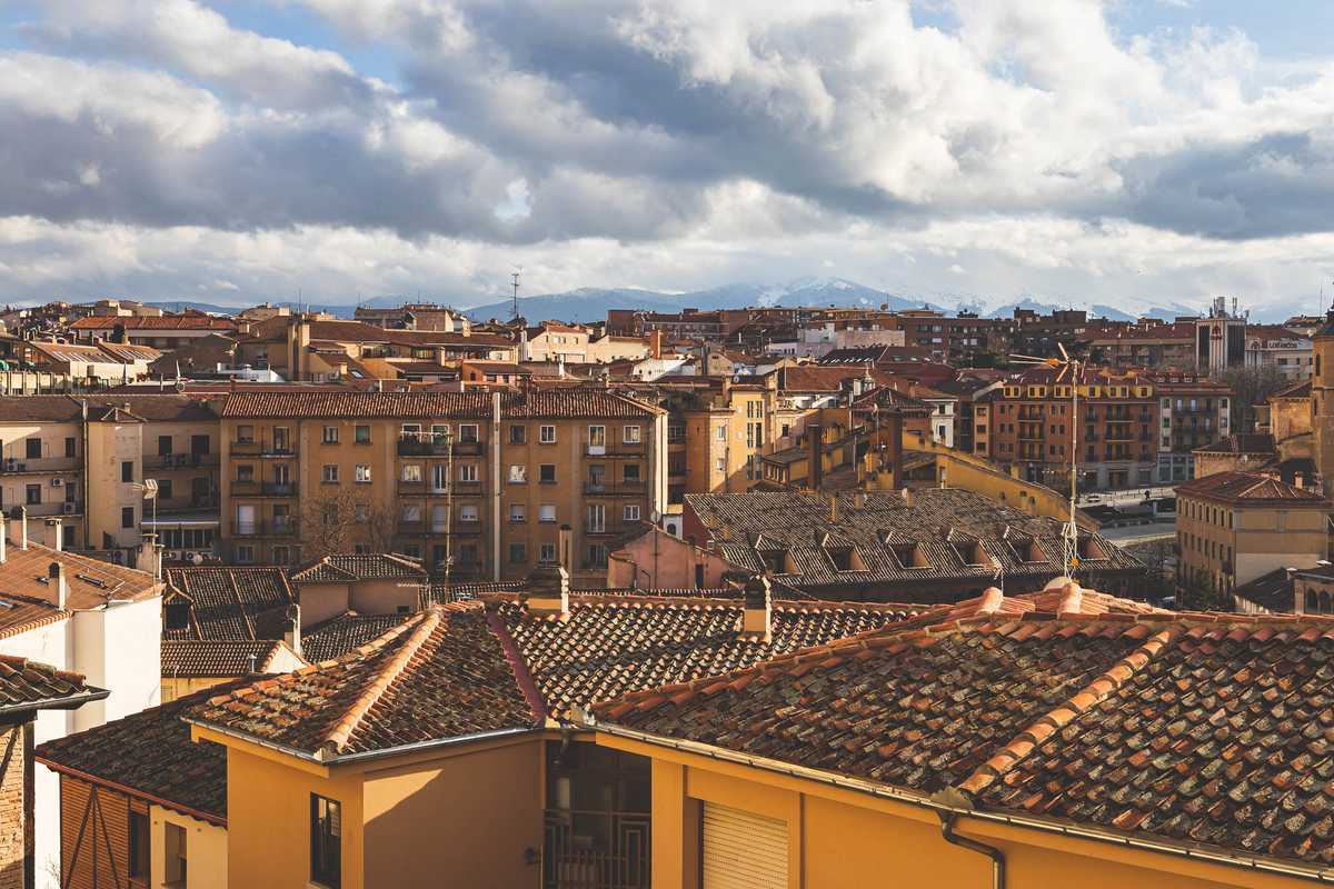 Another photo of the rooftops of Segovia, with snowy mountains shrouded in clouds behind