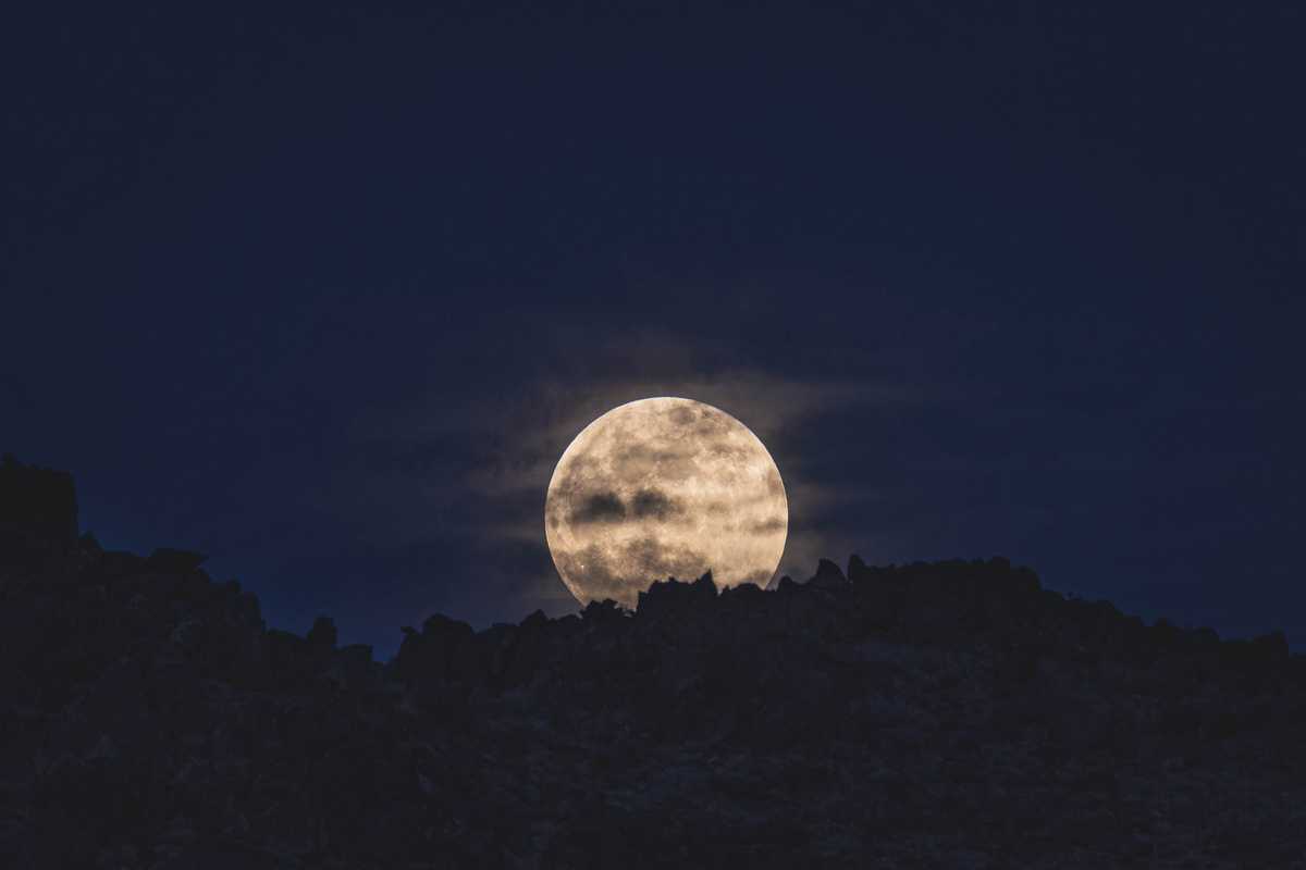 The moon rising over rock formations in Joshua Tree