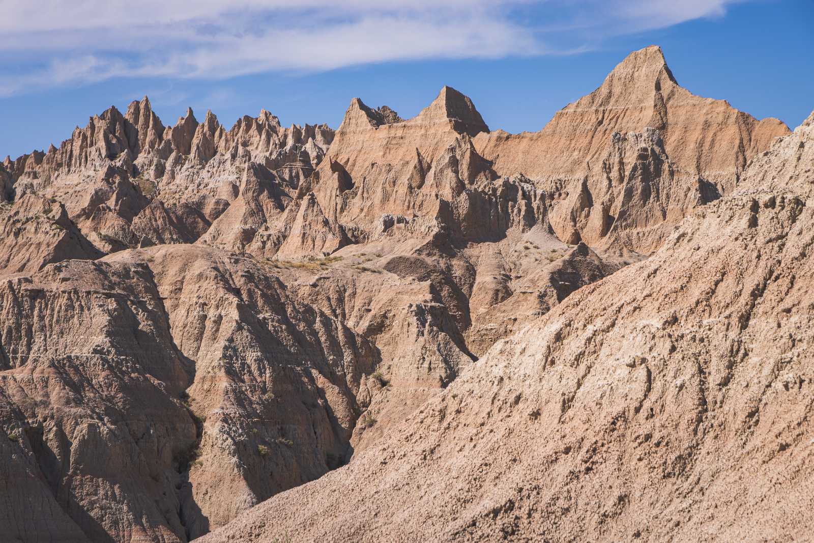 Mountains of smooth, tan sedimentary rock form sharp formations as they stretch high into the sky