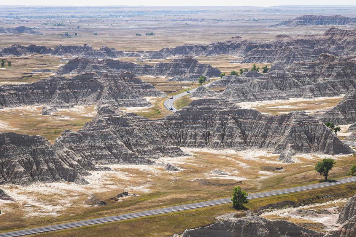 The roads of Badlands National park wind between rock formations and grassland into the distance