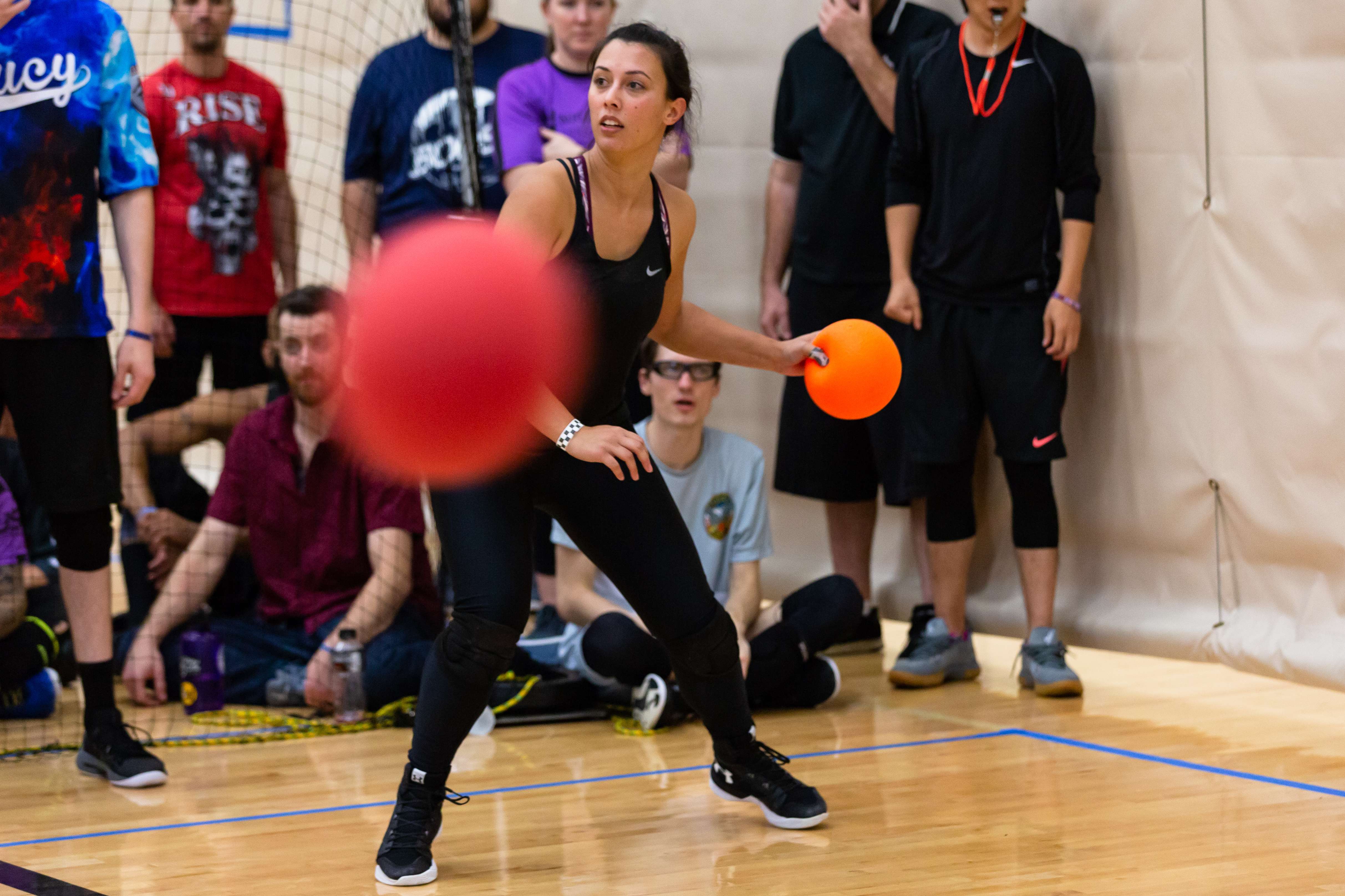 A dodgeball player surveys the field with an arm outstretched ready to throw
