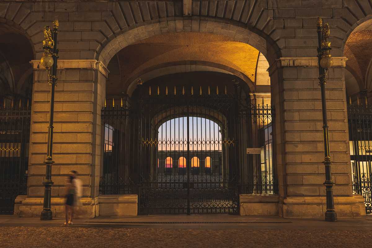 The sun sets behind a gate in the Royal Palace complex