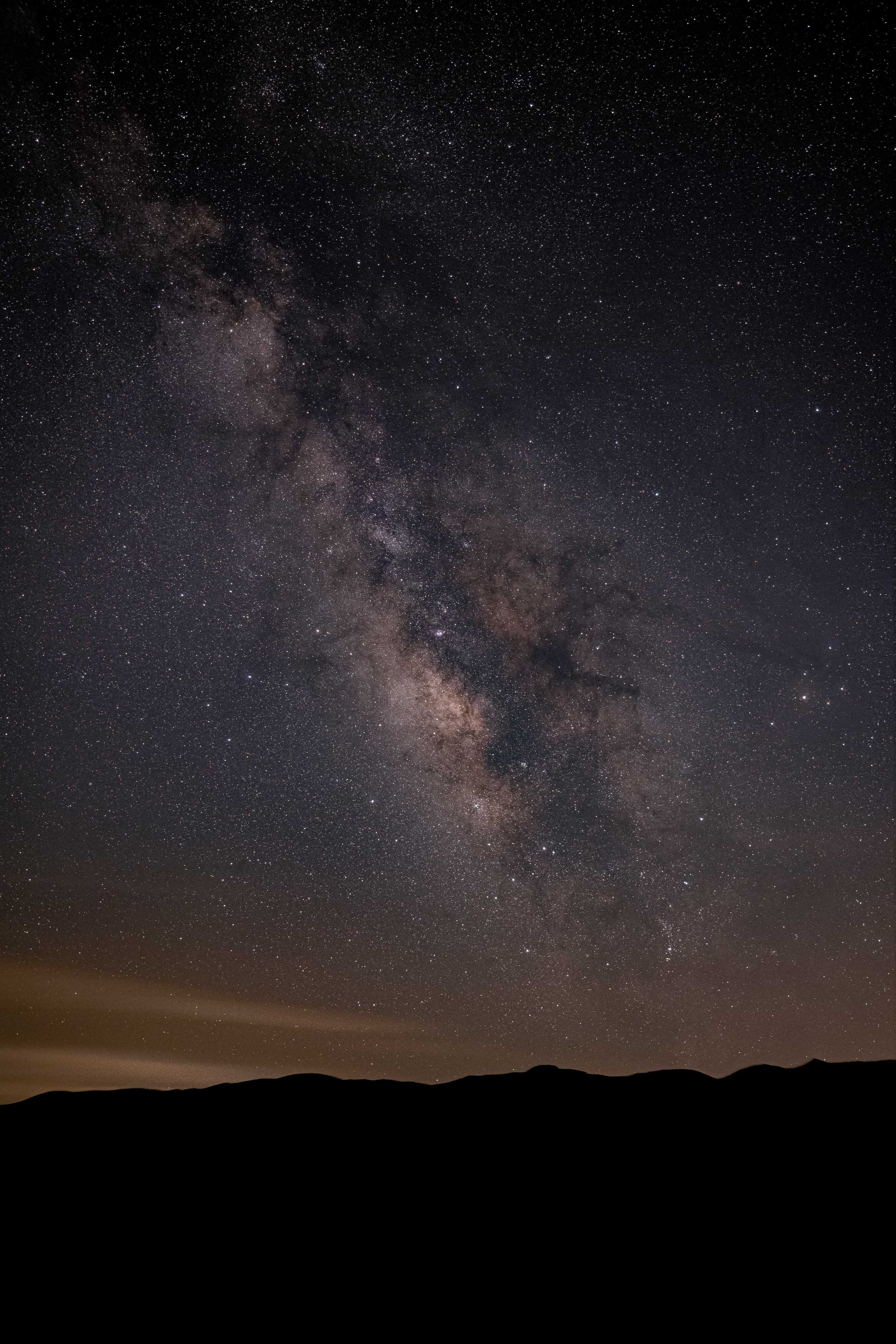 The almost infinte stars that form the bands of the milky way galaxy swirl in the night sky over a mountainous horizon
