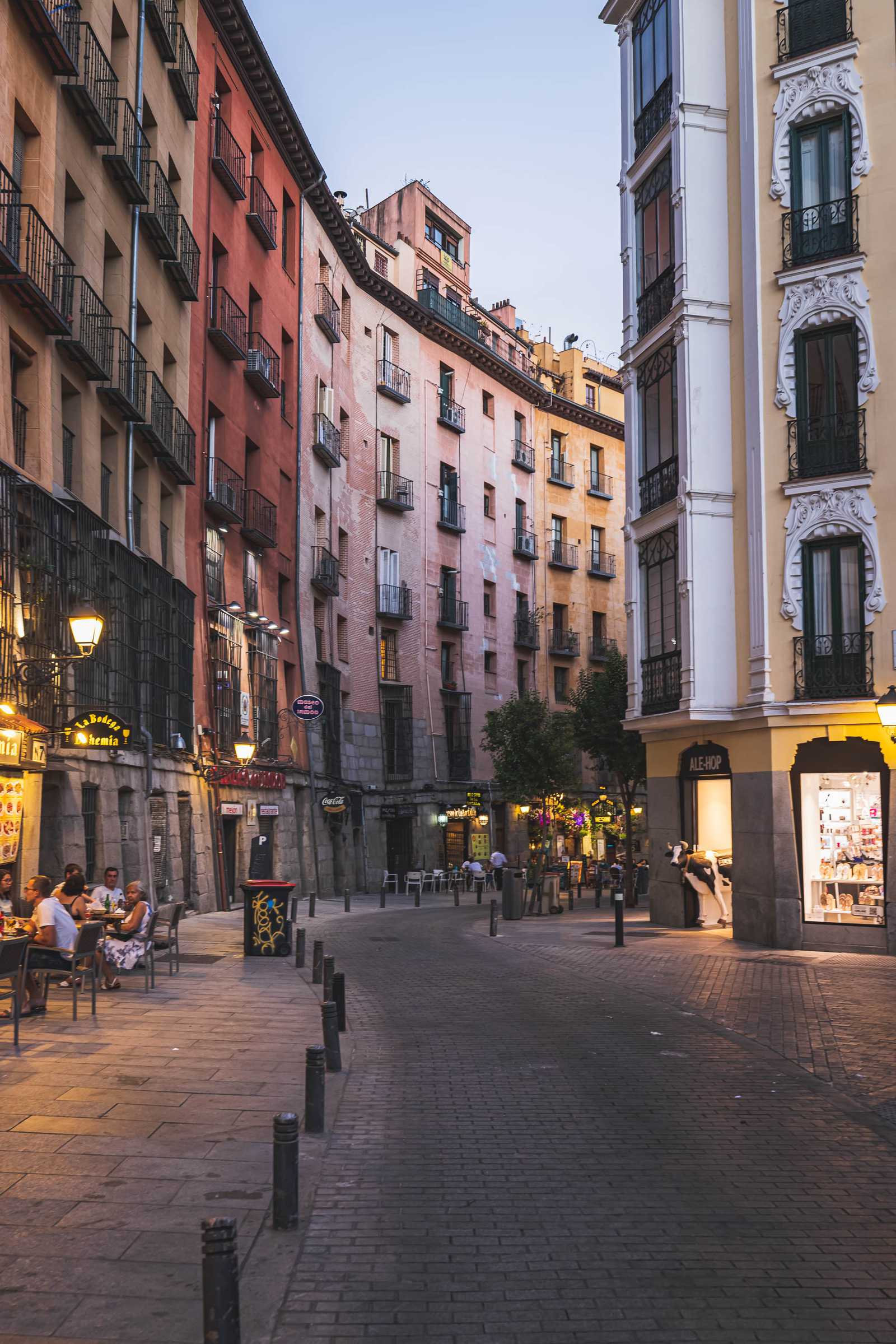 A typical Madrid street winds around a corner with shops and cafes on either side