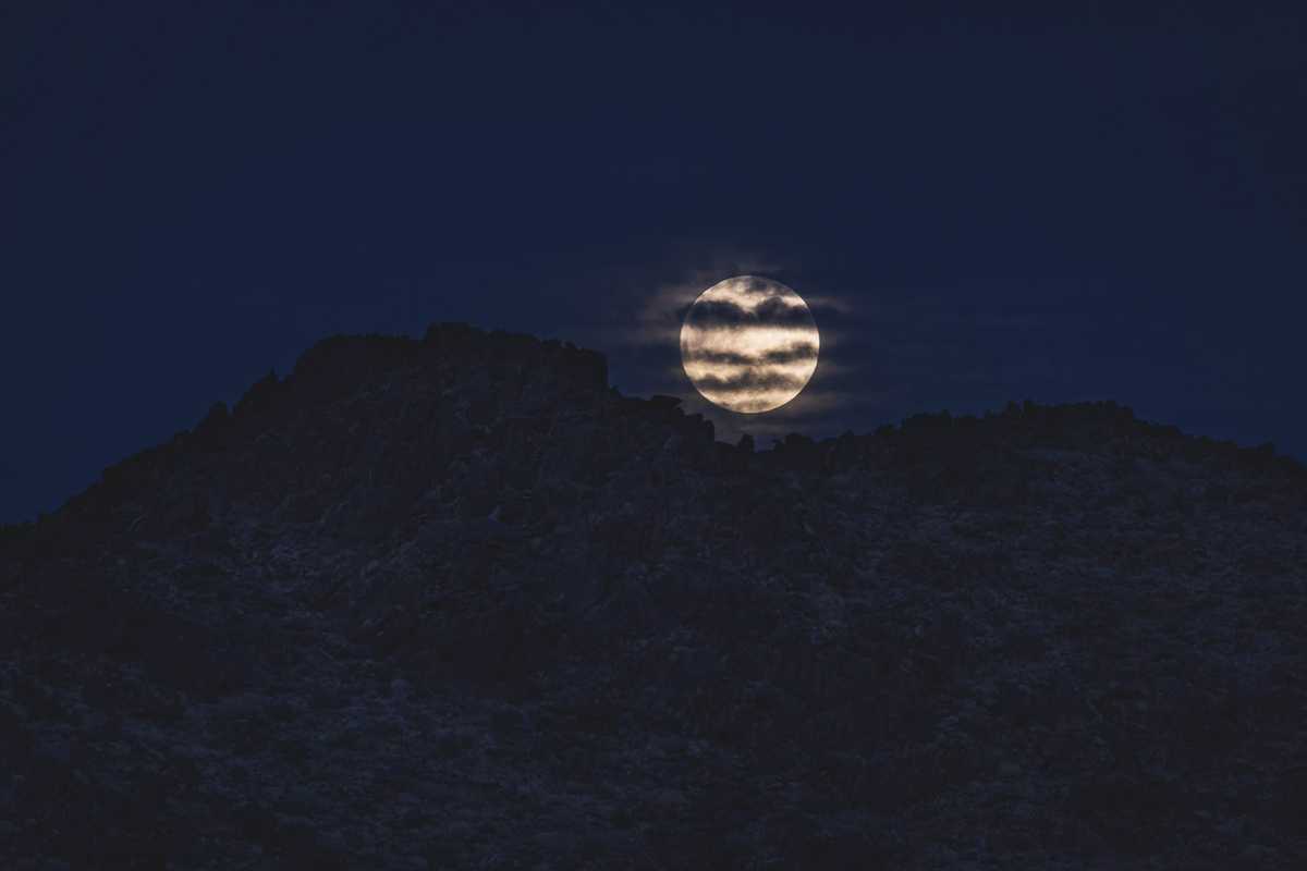 The moon rising over rock formations in Joshua Tree